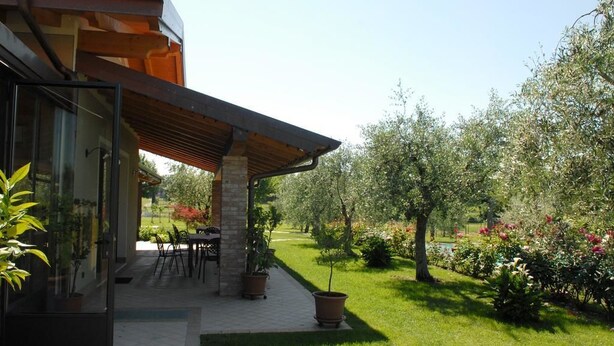 A modern house with a covered patio, outdoor seating, and a well-maintained garden. - Locanda dei Rii (Manerba del Garda)