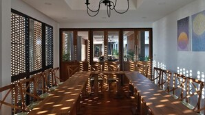 Un espace repas avec une longue table en bois, des chaises et un lustre.