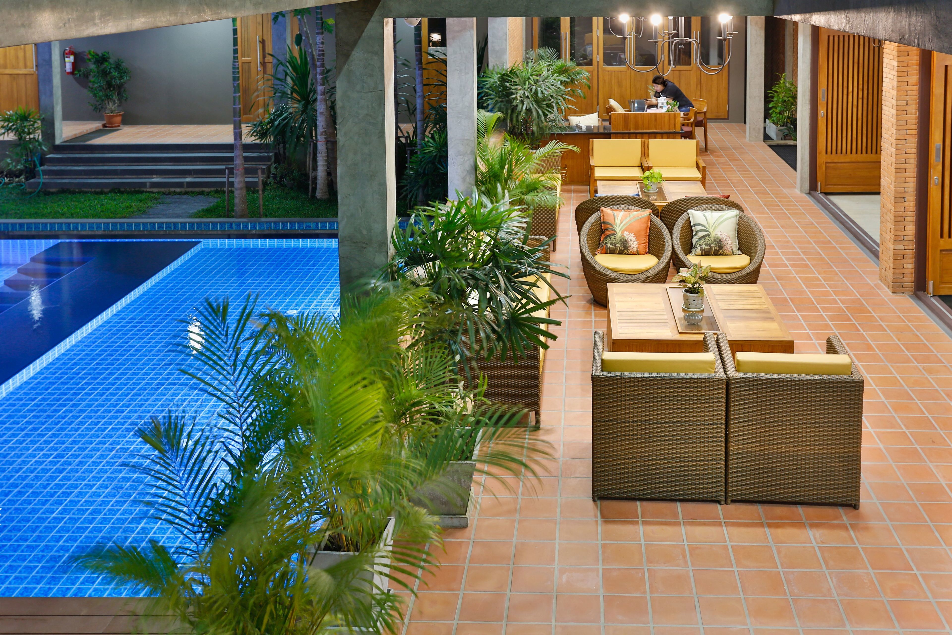 Un área junto a la piscina con mobiliario de comedor y sillones de descanso.