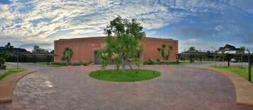 Un edificio con una entrada circular, un árbol central y fachada de ladrillo.