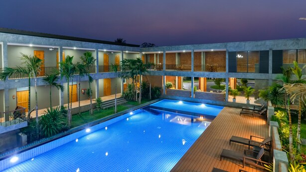 Un hôtel à plusieurs étages doté d’une piscine centrale, d’un espace extérieur aménagé et d’une végétation luxuriante.