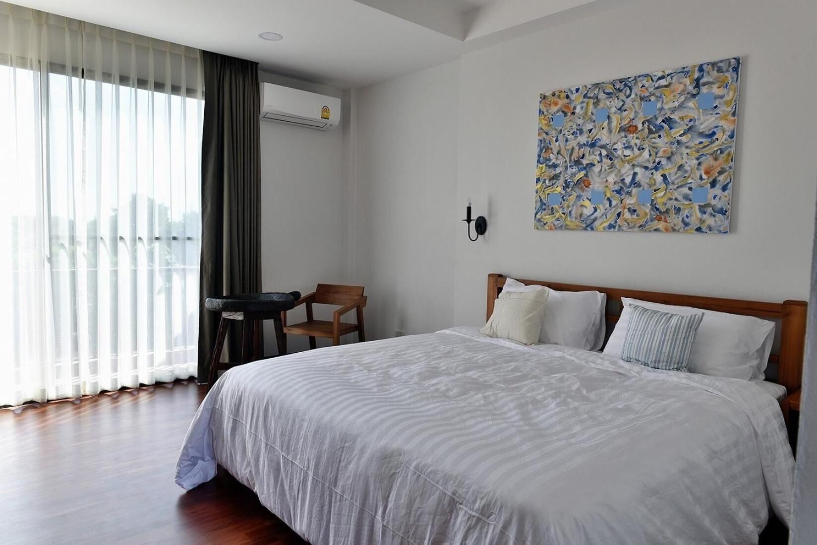 Habitación de hotel con una cama grande, un escritorio, una silla y vista a la ciudad desde la ventana.