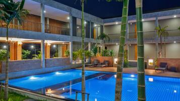 Una piscina al aire libre, sombrillas, sillones reclinables de piscina