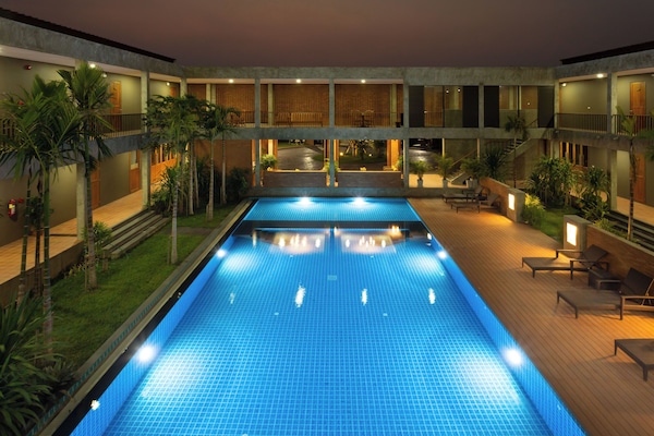 Una piscina al aire libre, sombrillas, sillones reclinables de piscina