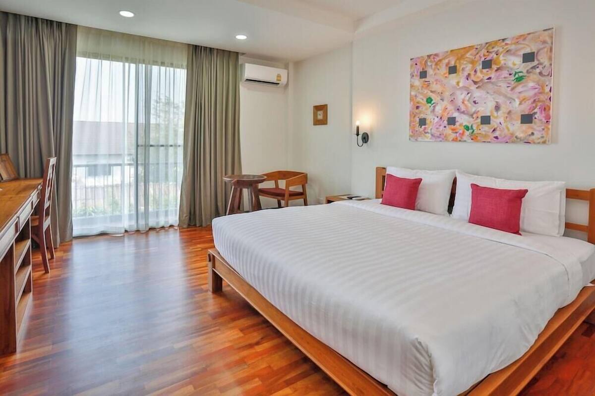 Habitación de hotel con una cama grande, un escritorio, una silla y una ventana con cortinas.