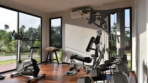 Une salle de sport moderne équipée de machines de cardio, de poids libres et d’un rameur.