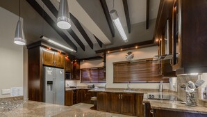 A modern kitchen with granite countertops, wooden cabinets, stainless steel appliances, and pendant lighting. - San Lameer Villa Rentals 403 (Southbroom)