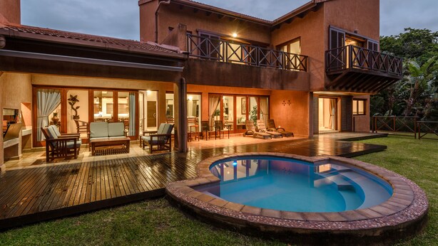 A two-story house with a swimming pool, outdoor furniture, and a balcony. - San Lameer Villa Rentals 403 (Southbroom)