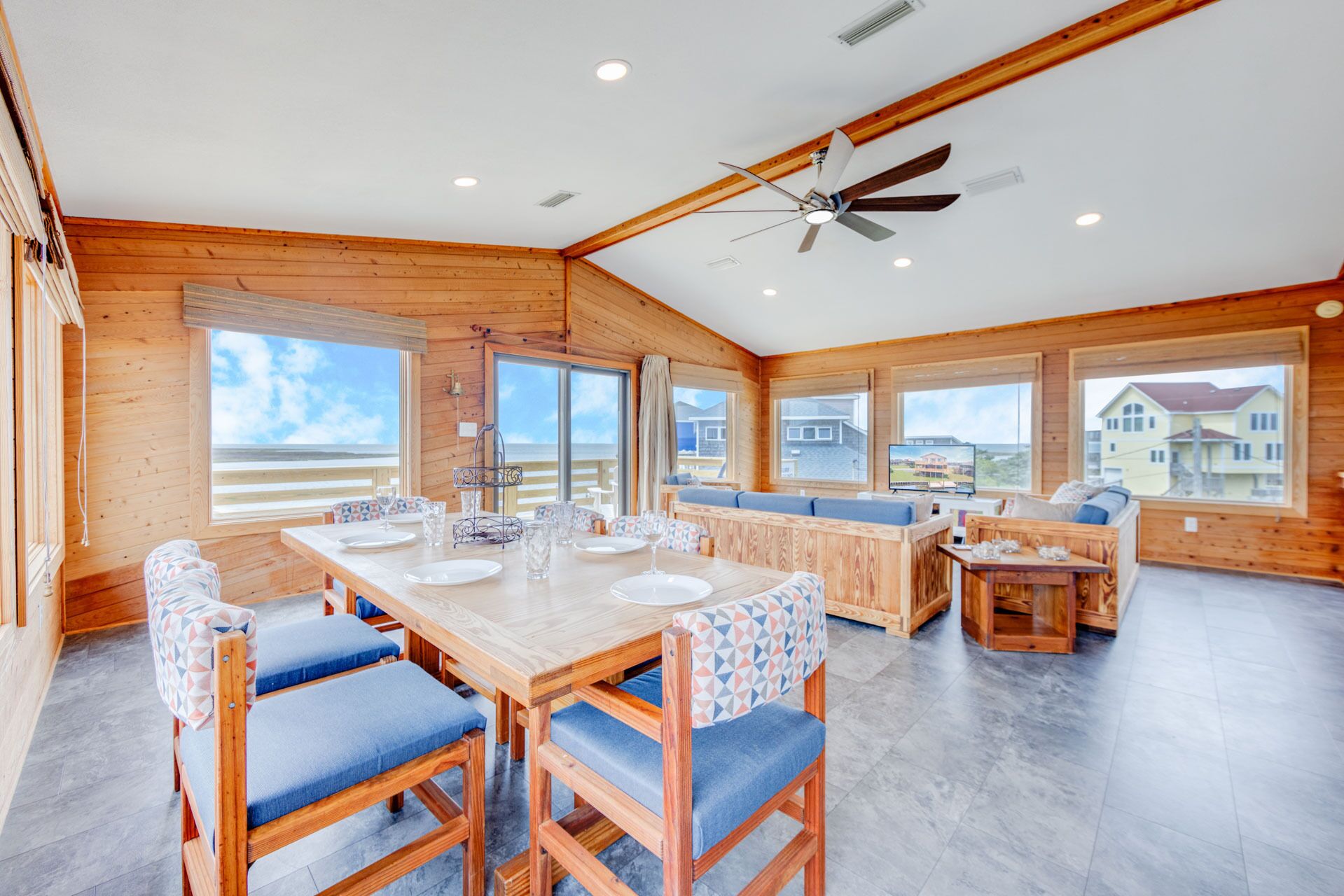 A spacious room with a wooden interior, a large dining table, and a ceiling fan.