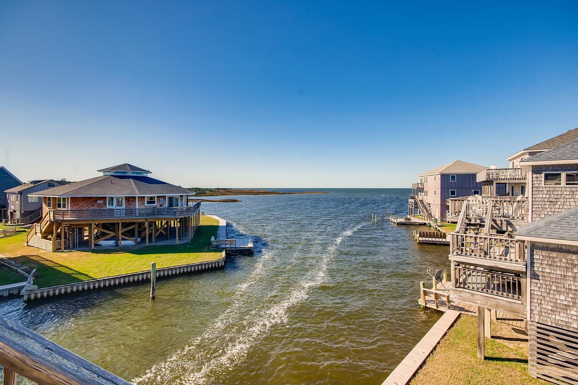 A waterfront property with a dock, a house with a balcony, and a pier extending into the water.