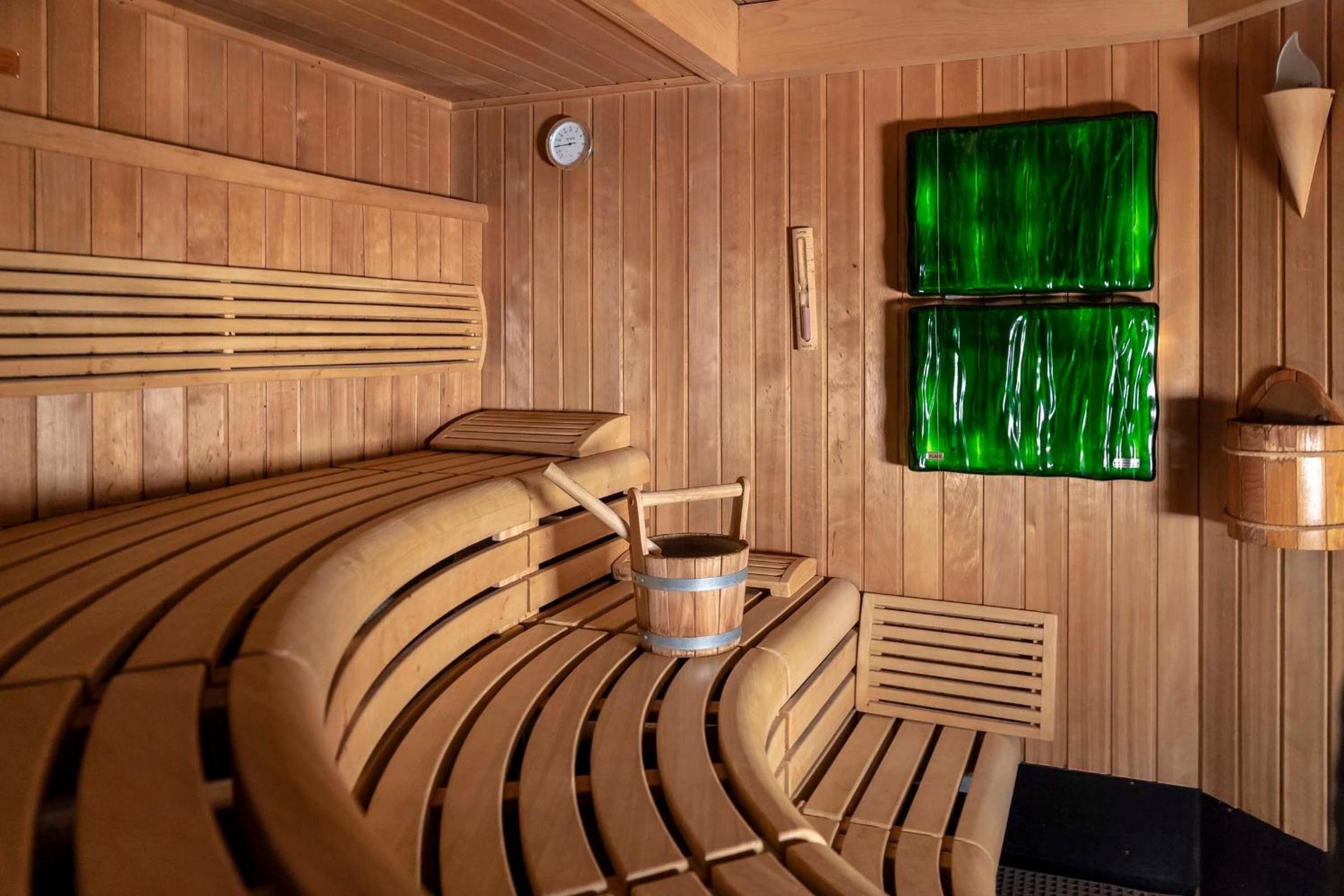 A sauna with wooden benches and a bucket.