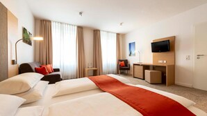 A hotel room with a large bed, a desk, a chair, a TV, and a window with curtains. - Hotel Gasthof Krone (Niederstetten)