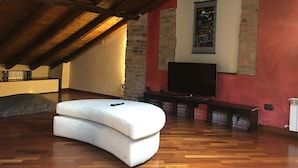 A cozy attic room with a wooden ceiling, a flat-screen TV, and a white sofa. - Luxury apartment located 500 metres from  historic centre and railway station (Varese)