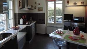 A modern kitchen with a dining area, featuring a large window, a red pendant light, and a microwave. - Luxury apartment located 500 metres from  historic centre and railway station (Varese)