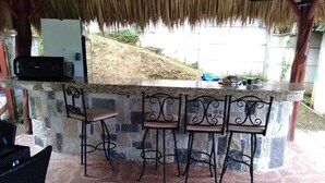 An outdoor bar area with a stone countertop and metal chairs. - beuatifull house in the mountains with beach view (Savegre)