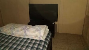 A hotel room with a bed, a television on a stand, and a plain wall. - beuatifull house in the mountains with beach view (Savegre)