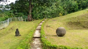 A pathway leading through a grassy area with a Buddha statue and a large spherical stone on the right. - beuatifull house in the mountains with beach view (Savegre)