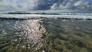 A beach with waves and sunlight reflecting on the water.