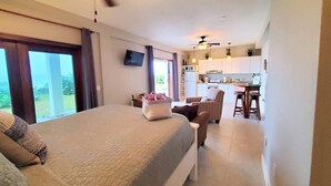 A bedroom with a bed, a chair, a table, and a view of the outdoors.