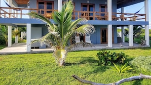 A two-story house with a balcony, a palm tree, and a well-maintained lawn.