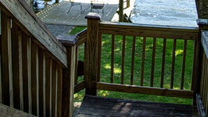 A wooden deck with a railing overlooking a body of water, a dock, and a boat.