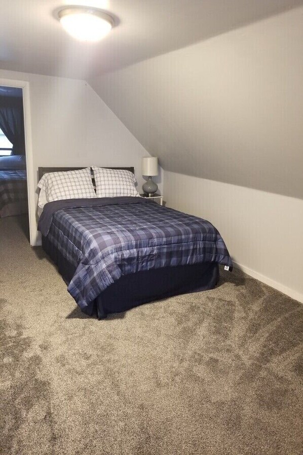 A bedroom with a bed, a nightstand, and a ceiling light.