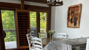 Ein geräumiger Essbereich mit Marmorplatte, weißen Stühlen und Blick durch große Fenster.
