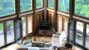 Ein Zimmer mit hohen Decken, großen Fenstern, einem Deckenventilator und einem Kamin.