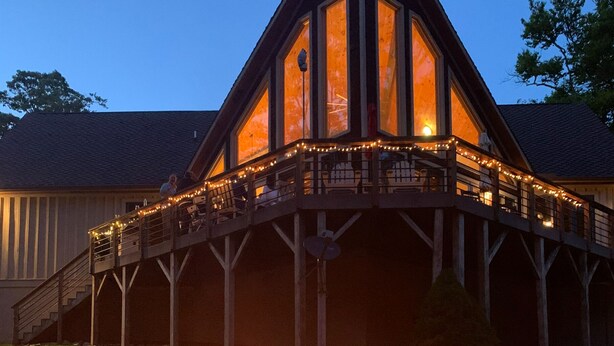 Eine Lodge mit Feuerstelle davor, einer überdachten Terrasse und einem großen, raumhohen Eingang.