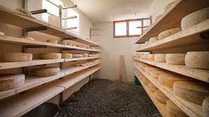 Una sala de añejamiento de queso con estantes de madera y suelo de grava.