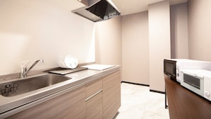 A modern kitchen with stainless steel appliances, wooden cabinetry, and a built-in microwave. - Hotel Chuo Bridge (Osaka)
