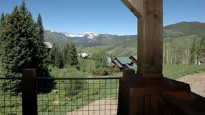 Une structure en bois offrant une vue sur des montagnes enneigées et une vallée boisée.
