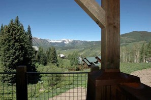 Une structure en bois offrant une vue sur des montagnes enneigées et une vallée boisée.