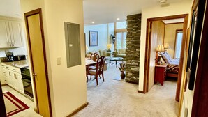 A spacious living area with a dining table, a stone accent wall, and a cozy seating area. - 3B Condo Overlooking Sugar Ski Slopes! (Sugar Mountain)