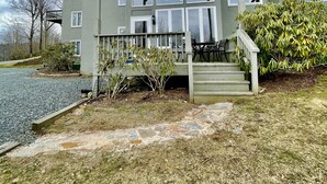 A multi-story building with a covered porch, a staircase, and a small garden area. - 3B Condo Overlooking Sugar Ski Slopes! (Sugar Mountain)