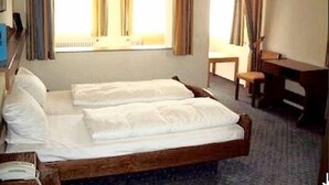 Una stanza con un letto in legno, una scrivania e una sedia.
