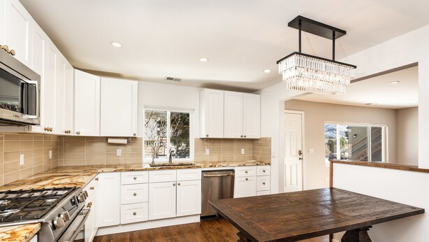 A modern kitchen with white cabinets, a wooden countertop, a built-in stove, and a chandelier. - Beautiful Home in Willits! (Basalt)