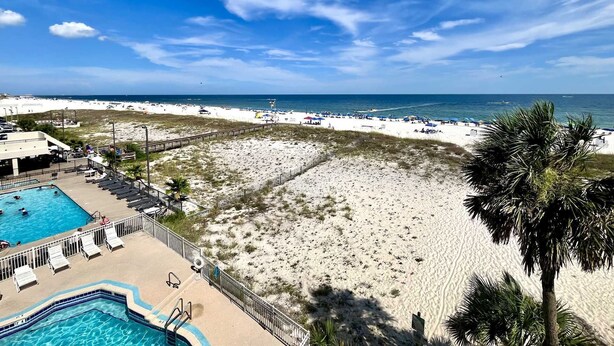 Un resort en la playa con piscina, sillas de playa y vista al océano.