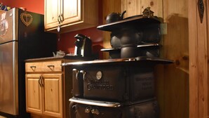 A kitchen with wooden cabinets, a black refrigerator, and a vintage Fortress Crawford stove.