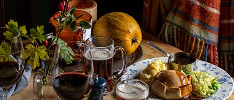 A dining table with a plate of food, a pumpkin, and several glasses of beer.