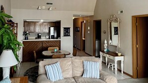 A spacious living area with a high ceiling, a ceiling fan, a kitchenette, a dining area, and a seating area with a sofa and a coffee table. - Relaxing Marvelous Main Channel View! (Lake Ozark)