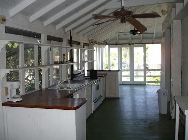 Uma cozinha com bancada de madeira, armários brancos e ventilador de teto.