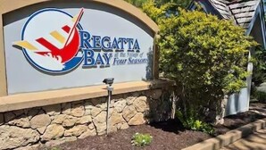 Un panneau indiquant l’entrée de Regatta Bay, situé près du Villa Four Seasons, avec un logo, un drapeau américain et un mur en pierre.
