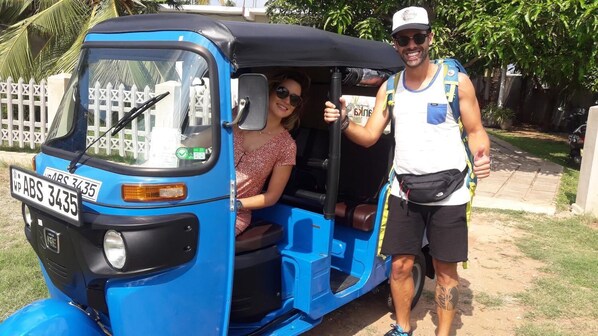 A blue auto-rickshaw with a visible license plate and a person standing beside it. - The Max Villa (Negombo)
