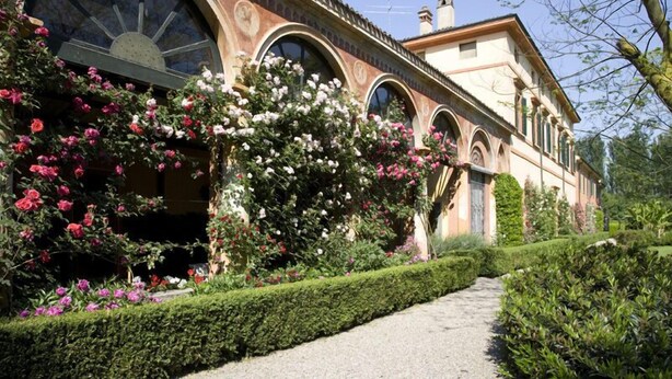Un bâtiment de style classique, doté de fenêtres en arc de cercle et d’un chemin qui traverse le jardin.