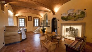 Un intérieur spacieux avec un comptoir d’accueil en bois, un escalier, un coin repas comprenant une table et des chaises, et une cheminée.
