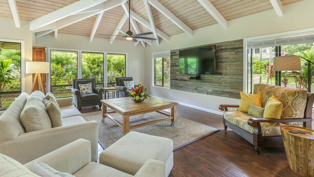 A spacious living room with a high ceiling, large windows, and a fireplace. - Open, bright, spacious home with AC in bedrooms, sleeps 9. (Princeville)