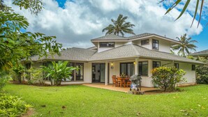 A two-story house with a covered patio, a dining area, and a barbecue setup. - Open, bright, spacious home with AC in bedrooms, sleeps 9. (Princeville)