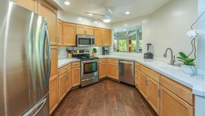 A modern kitchen with stainless steel appliances, wooden cabinets, and a white countertop. - Open, bright, spacious home with AC in bedrooms, sleeps 9. (Princeville)