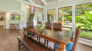 A spacious dining area with a long wooden table, comfortable chairs, and a ceiling fan. - Open, bright, spacious home with AC in bedrooms, sleeps 9. (Princeville)